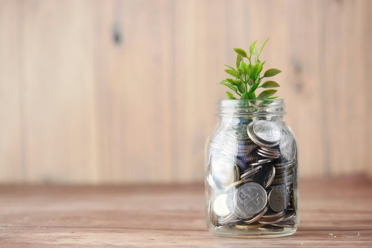 money jar with coins and a plant growing on it